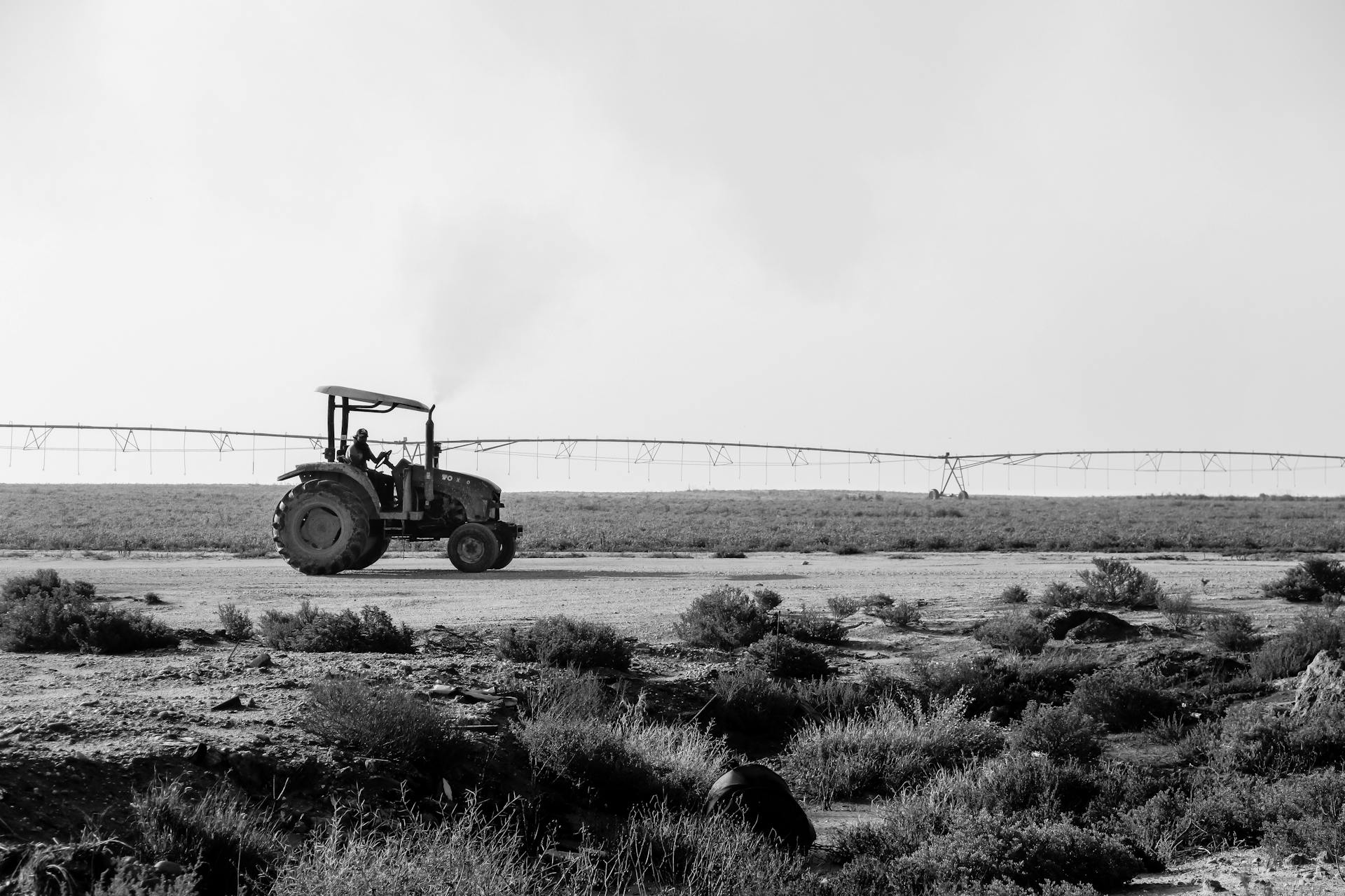 Black and white image of a tractor on a Qatari farm with irrigation system.