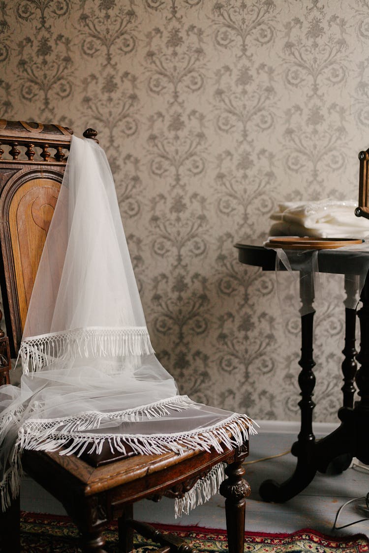 White Fabric With Fringe Draped Over Chair