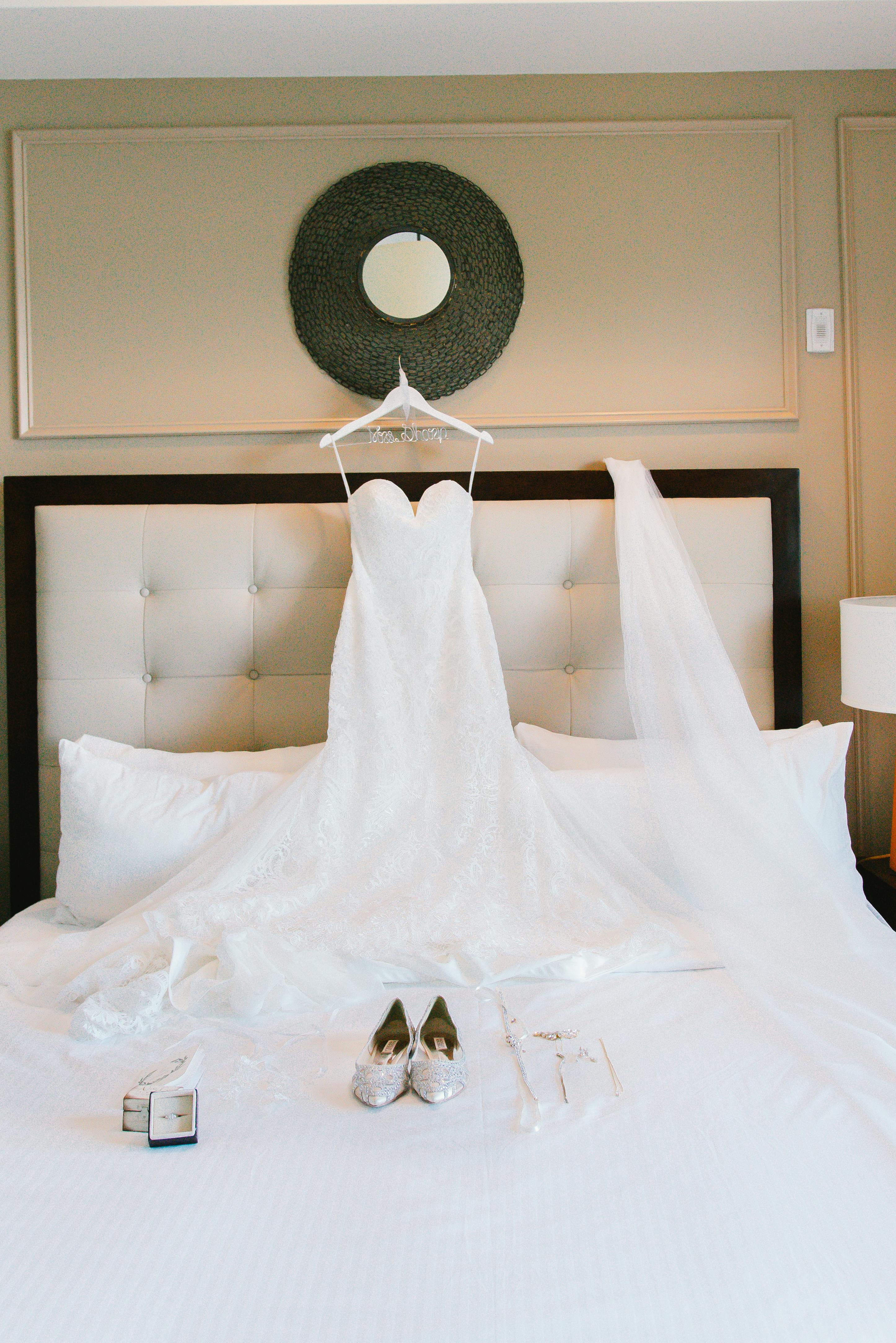 Beautiful lace wedding dress on bed with stylish shoes, ready for a special day.