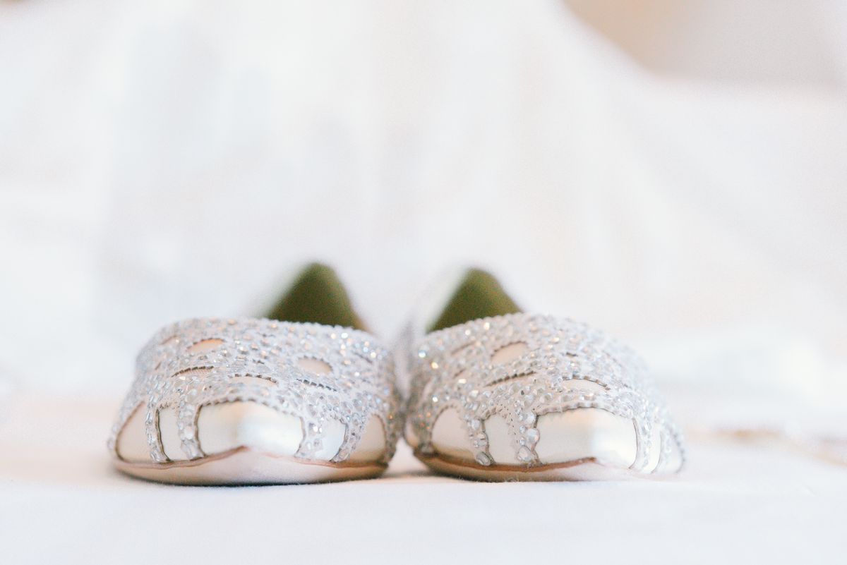 Ivory ballet flats with crystal embellishment photographed against soft white fabric