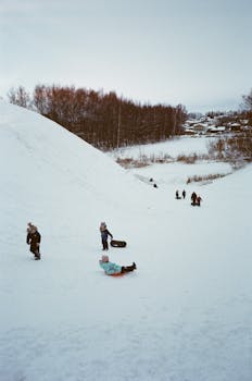 Children enjoying winter sledding on a snow-covered hill in Suzdal, Russia.