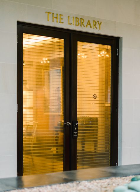 Sophisticated glass doors with blinds mark the entrance to a modern library facility.