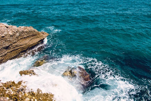Waves crash against rugged rocks on a scenic coastline in Córdoba, Spain, showcasing the ocean's power.