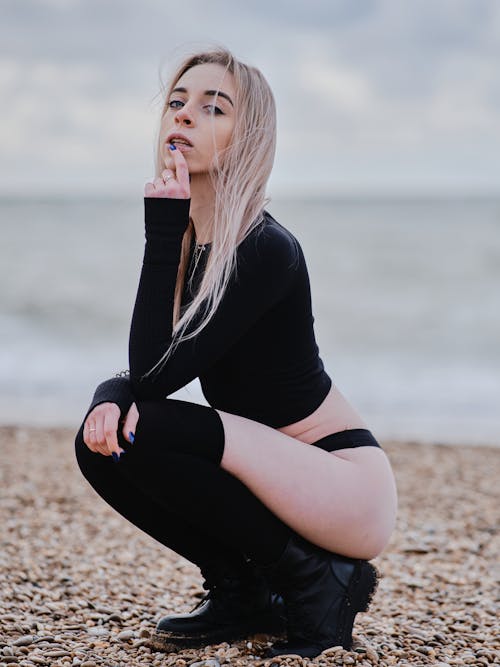 A Woman in Black Long Sleeve Shirt and Black Socks Sitting on Brown Sand