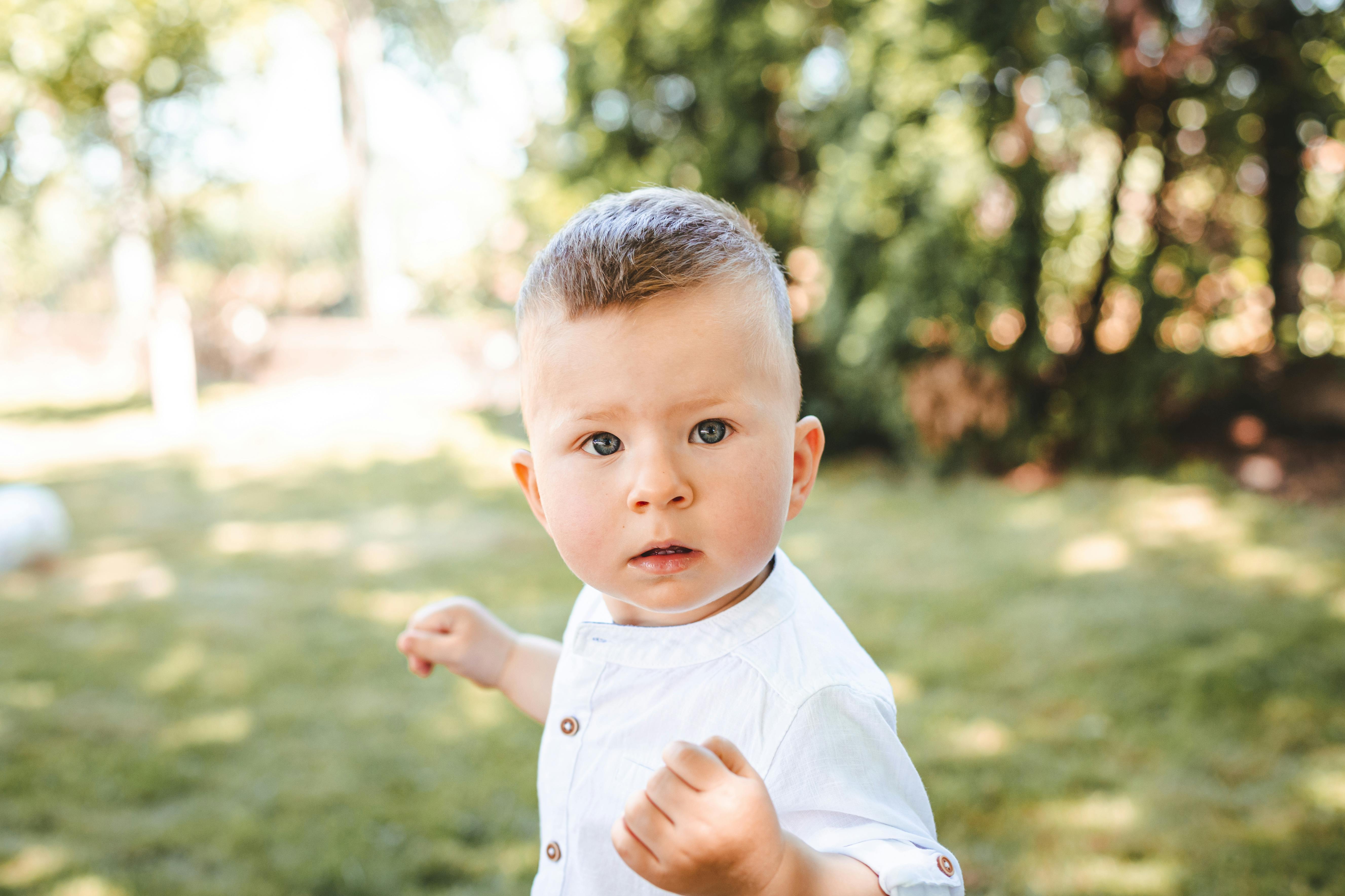 baby boy in white polo shirt standing on grass