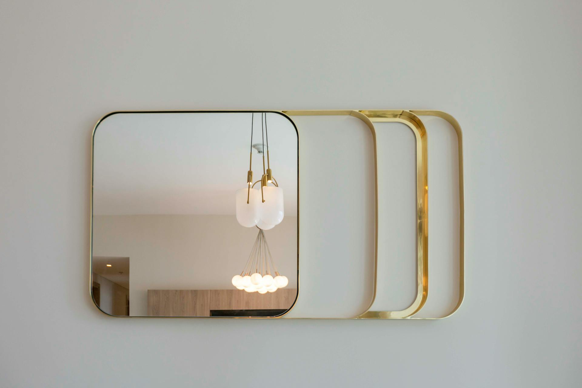 Stylish wall mirror with gold frame reflecting contemporary lighting in Dubai interior.