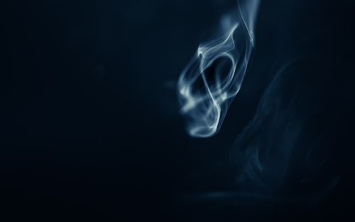 Free Ethereal smoke shapes delicately swirling on a dark background. Perfect for mysterious, abstract themes. Stock Photo