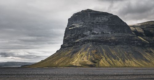 Free Lomagnupur Mountain stands majestically under a cloudy sky in Iceland's rugged terrain, offering a dramatic natural scene. Stock Photo