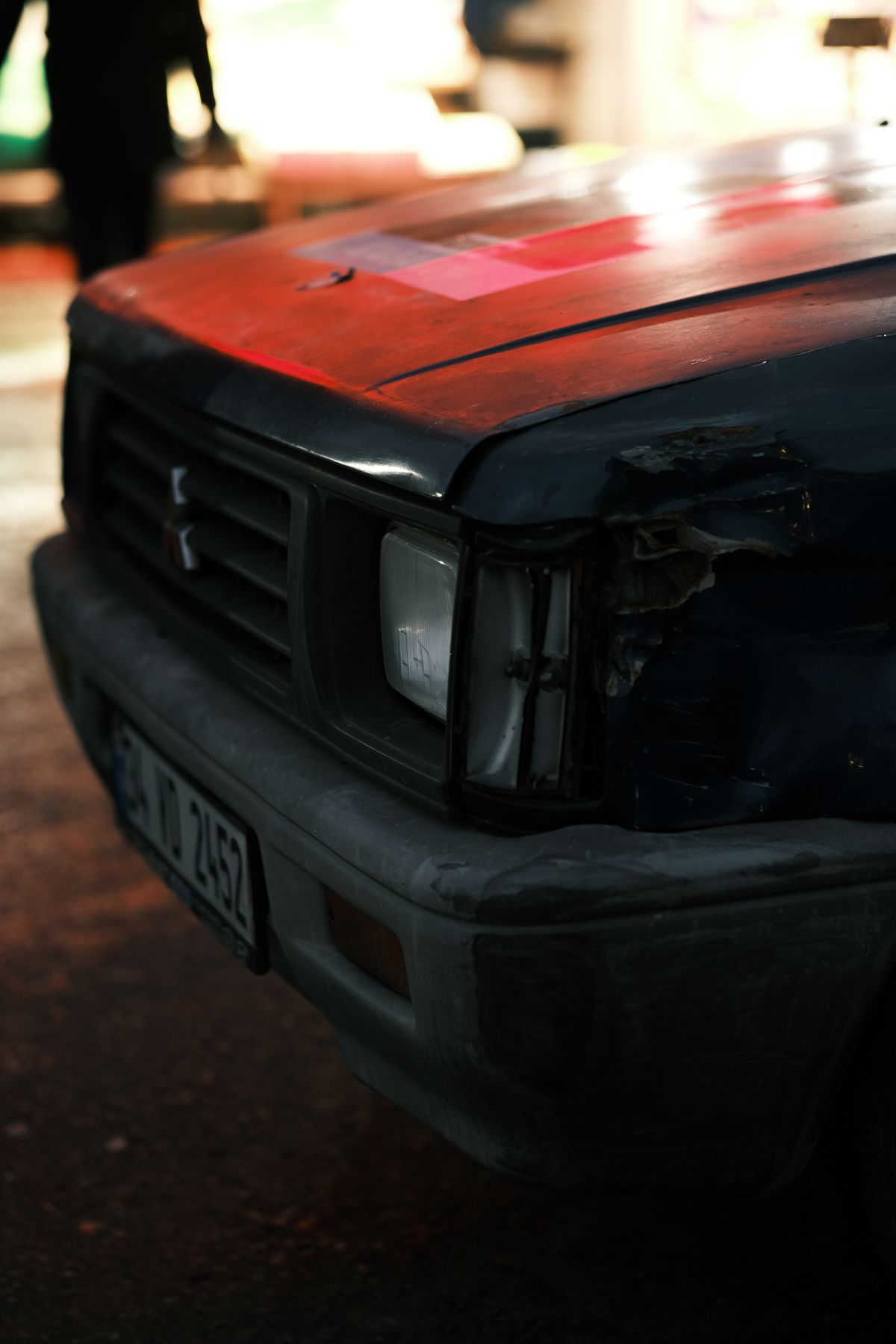 Close-up of a car with a damaged, scratched grille and broken headlight after a collision