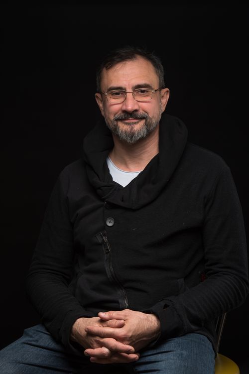 Free Studio portrait of a smiling mature man in glasses wearing a black jacket against a black background. Stock Photo