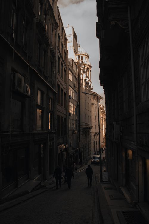 Free A narrow, cobblestone street in a historic city at dusk, featuring dramatic lighting and classic architecture. Stock Photo