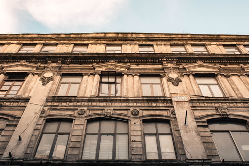 Free Detailed view of a historic stone facade showcasing classical architecture with windows. Stock Photo