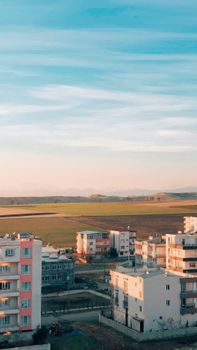 A beautiful aerial view of suburban buildings bordered by vast fields under a clear sky.