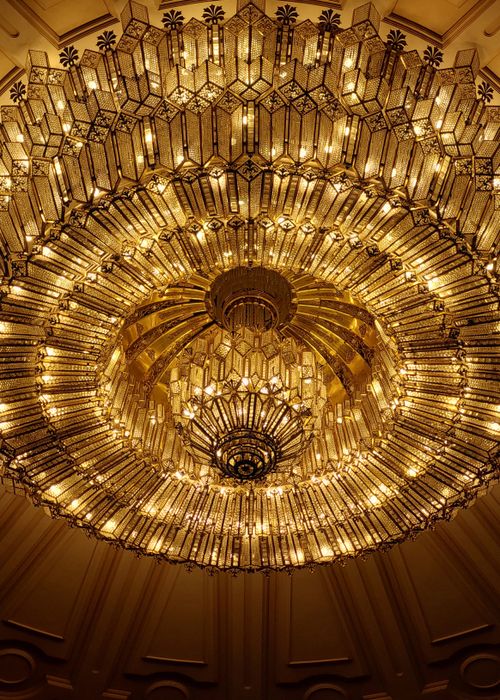 Free A stunning crystal chandelier with intricate design illuminated from below, showcasing a golden glow. Stock Photo