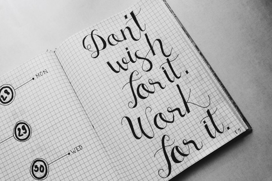 Close-up of motivational calligraphy on grid paper, inspiring message for productivity.