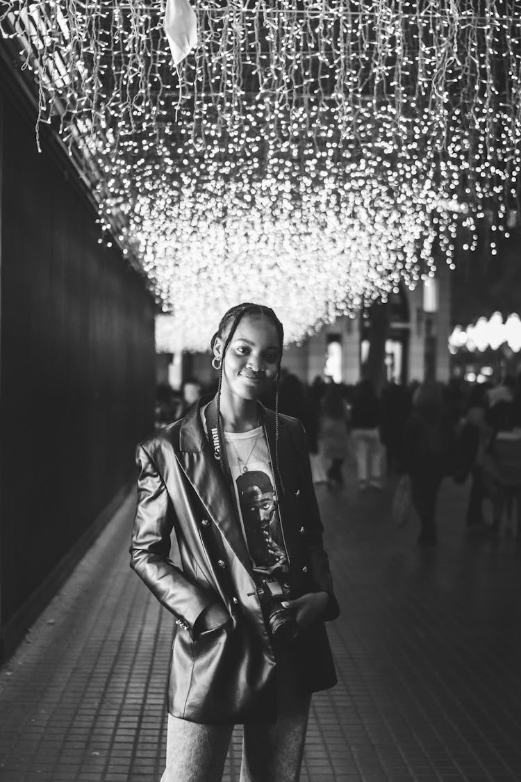 Woman In Black Leather Jacket Standing Below Christmas Illumination
