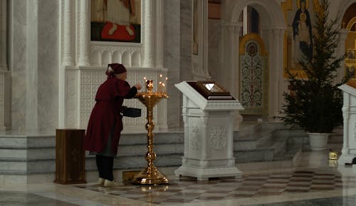 Priest Lighting Candles in a Church