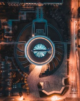 A mesmerizing aerial shot showcasing a vibrant circular building illuminated at night, surrounded by city streets.