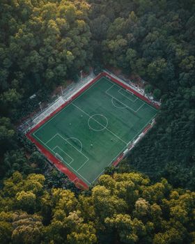 A stunning aerial view of a soccer field nestled in lush green forest surroundings.