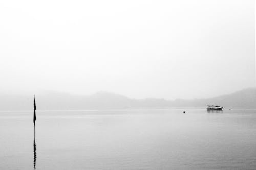 Grayscale Photo of a Boat on the Lake