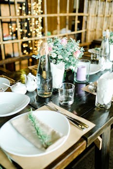 Beautiful table setup with flowers, candles, and cutlery in a warm, inviting atmosphere.