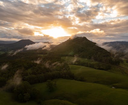 A breathtaking aerial view of Lynchs Creek, NSW at sunrise, showcasing misty mountains and lush green landscapes.