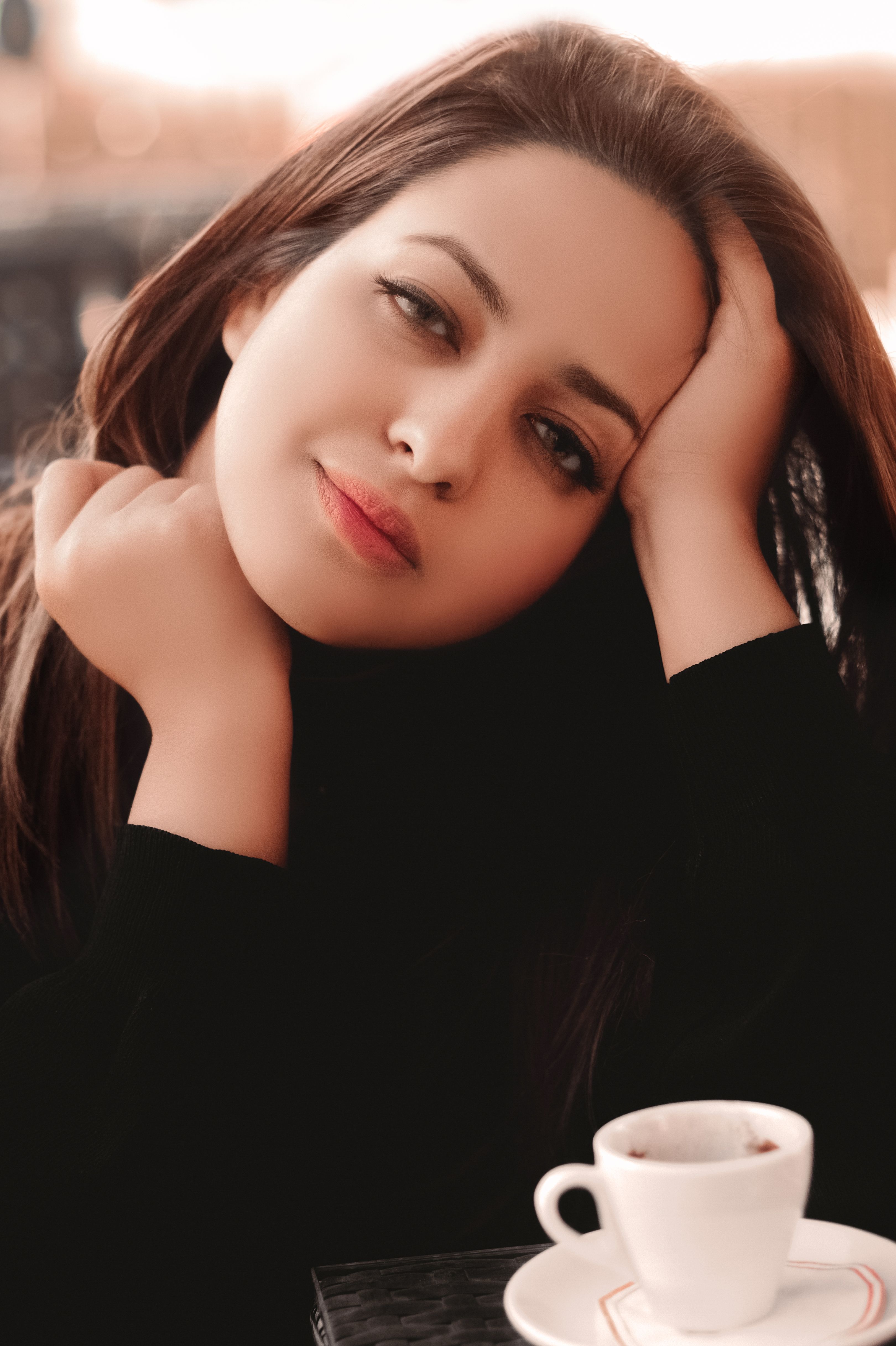 Portrait of a relaxed woman drinking coffee at a café, conveying elegance and warmth.