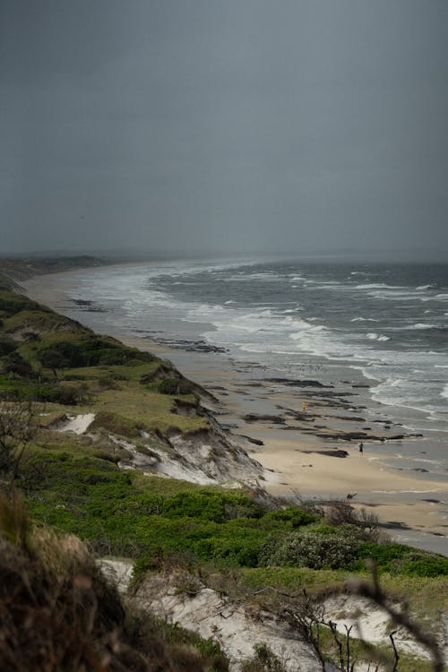 Crashing Waves on Beach Sand Under Gray Sky