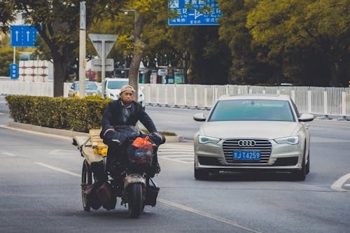Man Driving a Motorbike ad a Car Behind Him