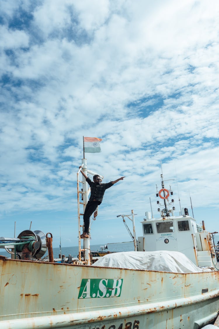 Man With Indian Flag On Vessel Under Clouds