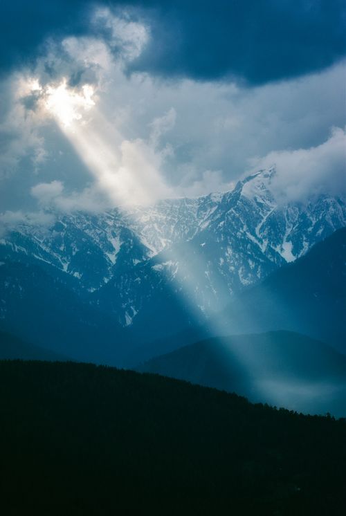 Free Majestic sunbeams illuminating snow-capped mountain peaks, creating a mystical dawn ambiance. Stock Photo
