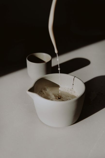 Aesthetic scene of milk being poured into coffee, emphasizing minimalism and soft lighting.