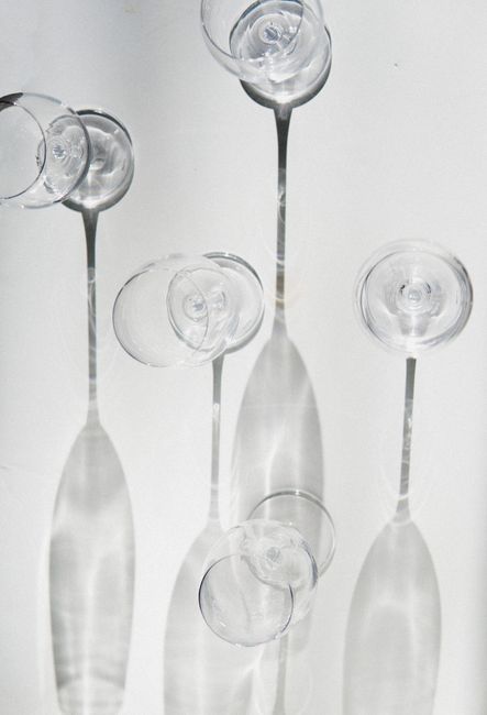 Artistic display of wine glasses casting intricate shadows on a white background.