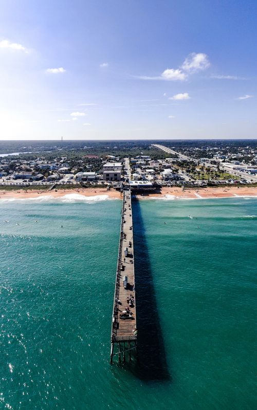 Free A stunning aerial shot of Flagler Beach pier extending into the turquoise ocean under a clear blue sky. Stock Photo