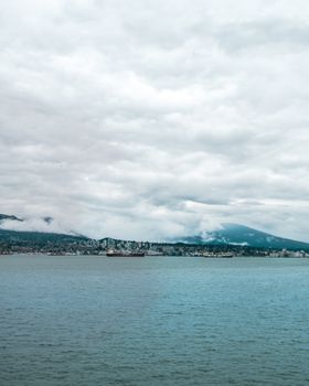 Capture of Vancouver harbor and skyline under thick, overcast skies creating a moody atmosphere.