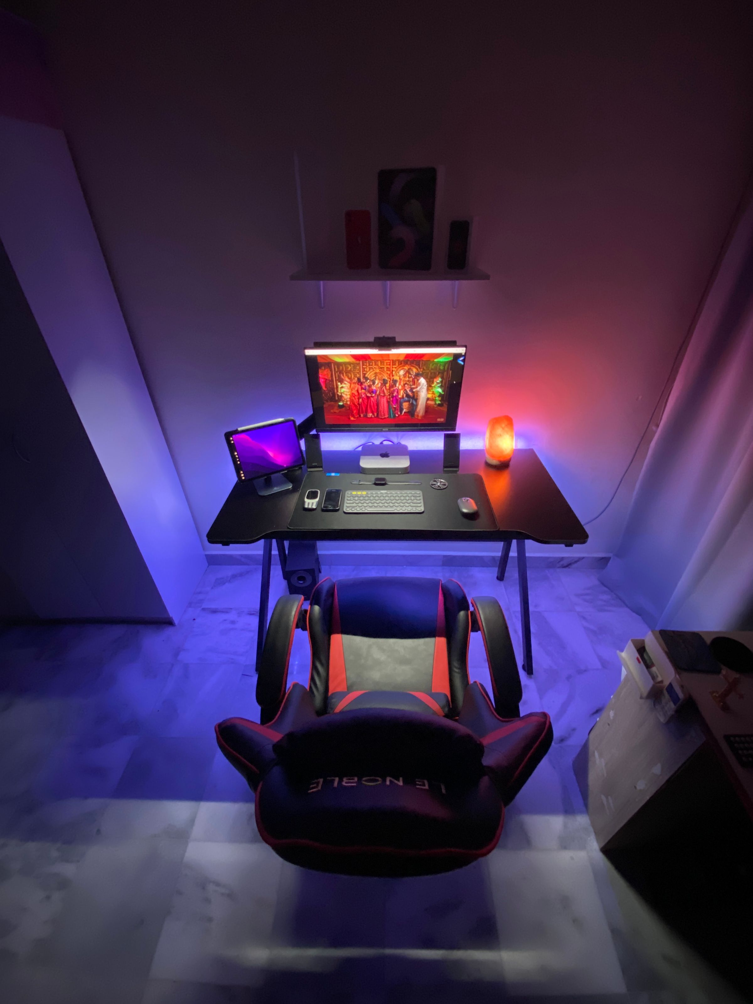Gaming chair and peripherals arranged around a complete desk setup