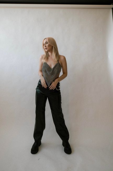 Blonde woman posing in fashionable attire during studio shoot.
