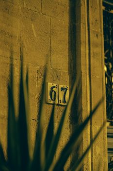 Night shot of a vintage building façade showcasing the number 67, illuminated in warm tones.
