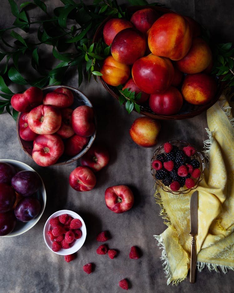 Plums, Raspberries, Nectarines In Bowls On Table