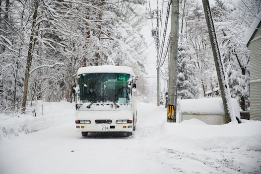 A snow-covered road with a bus navigating through heavy snow in Hakuba, Japan.
