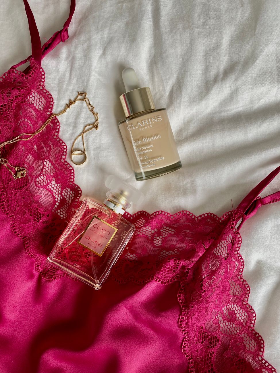 Stylish flat lay of pink lingerie, perfume, and beauty serum on white fabric.. stylish, flat, pink