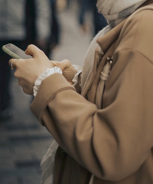 Person in Brown Coat Using a Smartphone