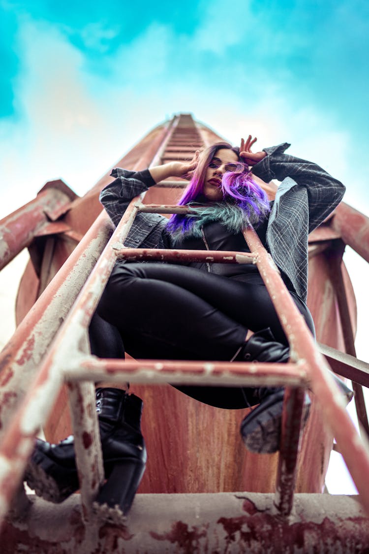 Woman In Black Long Sleeves And Pants Standing On A Metal Ladder