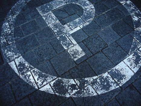 A detailed view of a weathered parking sign on a brick pavement in an outdoor setting.