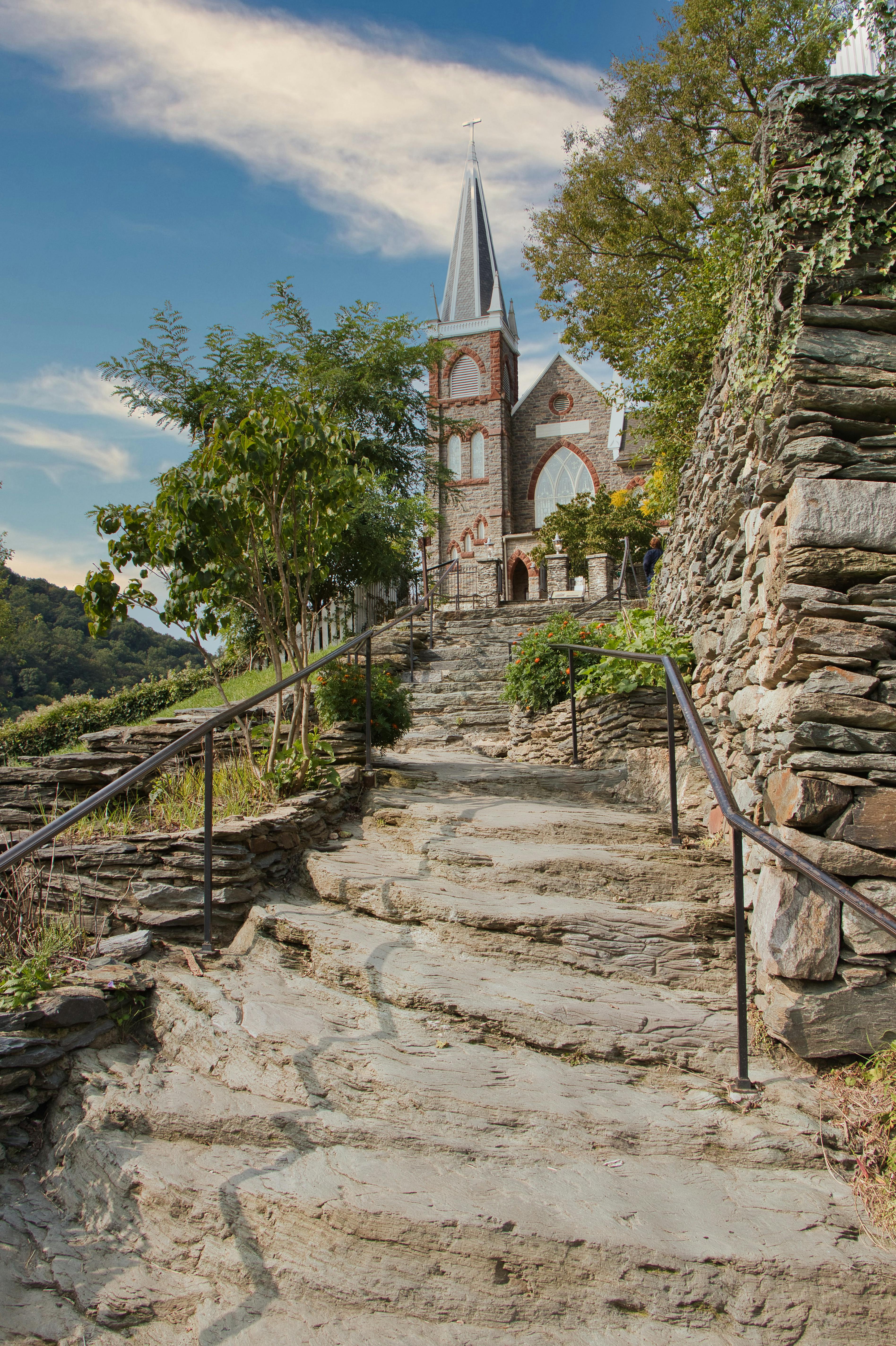 Stone pathway leading to historic church in Harpers Ferry, WV, surrounded by lush greenery.