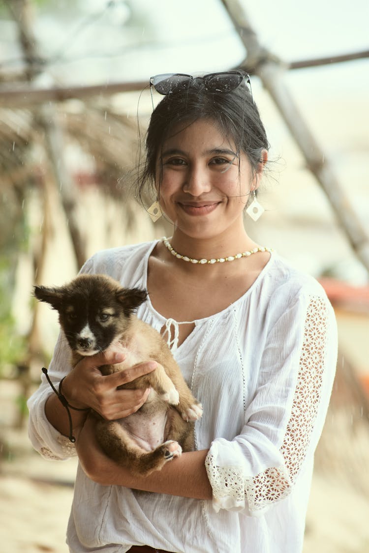 A Woman In White Top Holding A Puppy