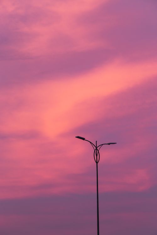 Free Silhouetted streetlight against a vivid pink twilight sky capturing a serene evening scene. Stock Photo