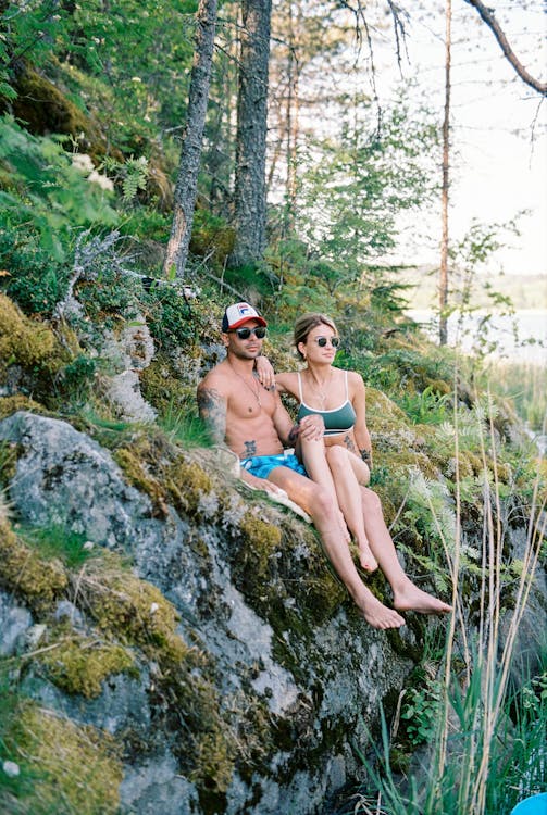 A Man and a Woman Sitting on Mossy Rocks