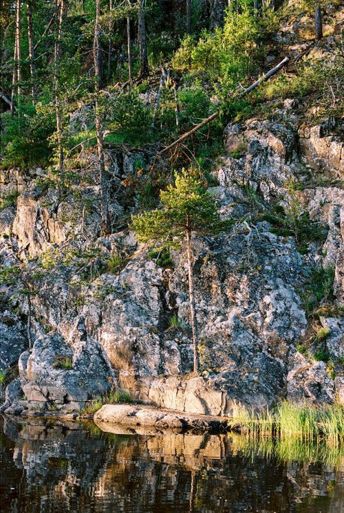 Free Stunning rocky landscape with green foliage reflecting in tranquil lake waters. Stock Photo