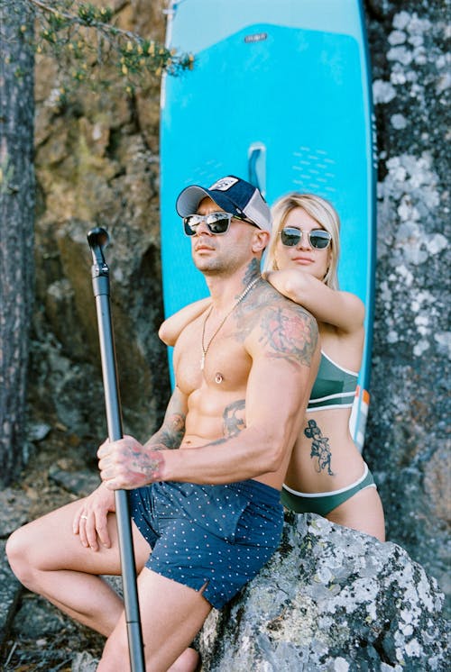 Couple with Tattoos on Beach with Surfboard 